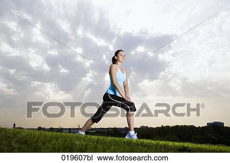 Stock Image - young jogger doing stretching exercises in park. Fotosearch