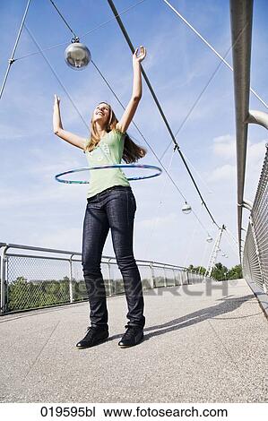 Stock Image - young woman doing hula hoop on bridge. Fotosearch