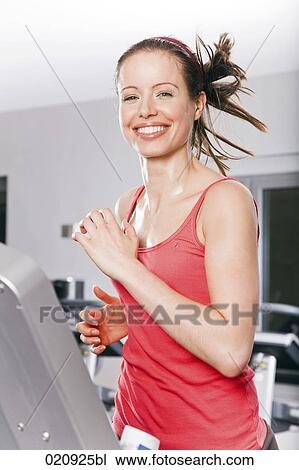 Stock Image - young woman exercising on treadmill in gym. Fotosearch