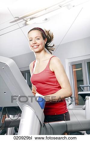 Stock Image - young woman exercising on treadmill in gym. Fotosearch