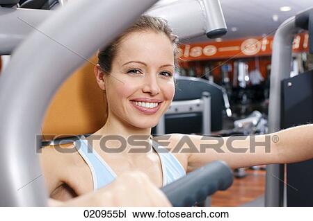 young woman exercising on weight machine in gym View Large Photo Image Stock Image - young woman exercising on weight machine in gym. Fotosearch