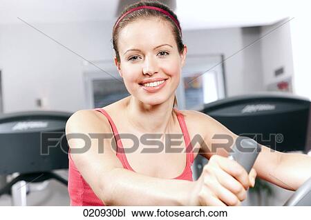 young woman exercising with stationary bicyle in gym View Large Photo Image Stock Image - young woman exercising with stationary bicyle in gym. Fotosearch