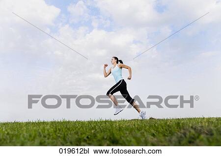 Stock Image - young woman jogging in park. Fotosearch