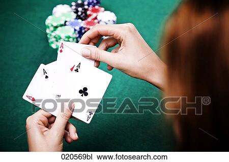 Stock Image - young woman playing poker holding three aces in hand. Fotosearch
