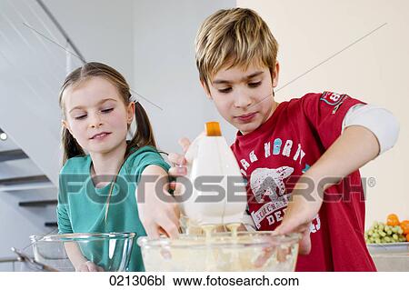 Stock Image - brother and sister mixing dough in bowl together. Fotosearch