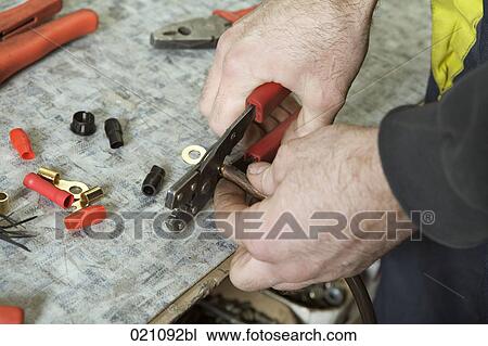 Stock Image - close-up of mechanic cutting cable using tongs. Fotosearch