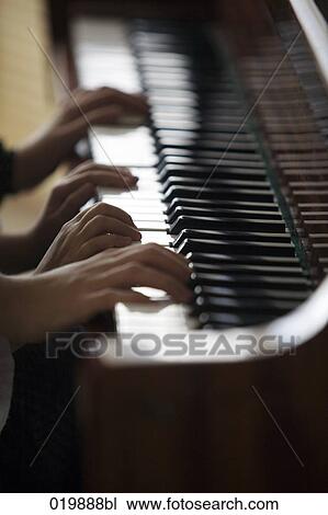 Stock Image - close-up of mother and daughter playing four handed piano. Fotosearch