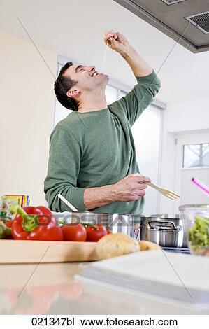 couple cooking in kitchen together man tasting spaghetti View Large Photo Image Stock Image - couple cooking in kitchen together man tasting spaghetti. Fotosearch