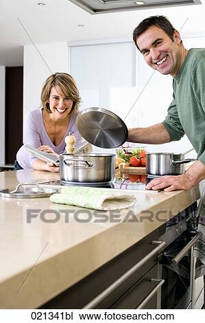 Stock Image - couple cooking together in kitchen. Fotosearch
