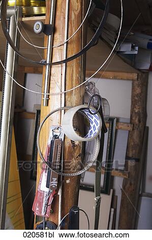 Stock Image - different tools hanging on post in workshop. Fotosearch