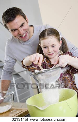 Stock Image - father and daughter making cake together. Fotosearch