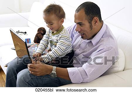 Stock Image - father showing his little son laptop computer. Fotosearch