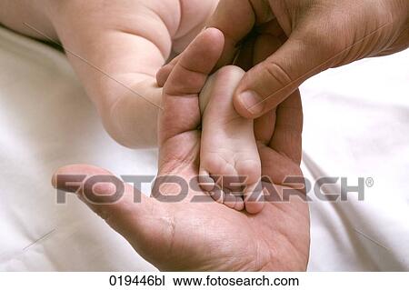 Stock Image - man holding tiny foot of baby. Fotosearch
