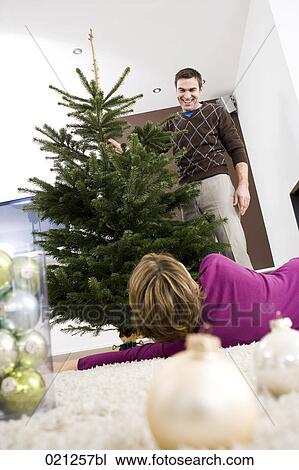 Stock Image - man presenting christmas tree to woman. Fotosearch