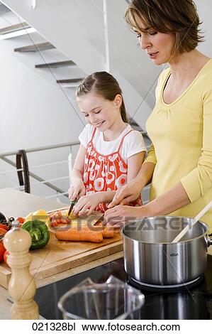 Stock Image - mother and daughter cutting vegetables. Fotosearch