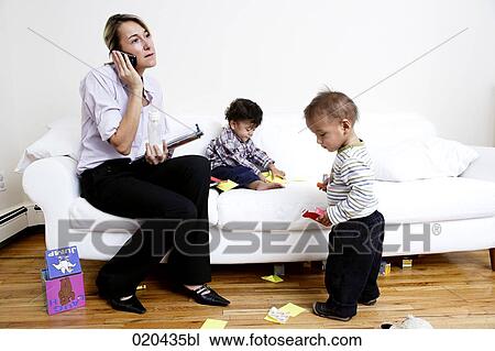 mother sitting on sofa talking on mobile phone while children are playing View Large Photo Image Stock Image - mother sitting on sofa talking on mobile phone while children are playing. Fotosearch