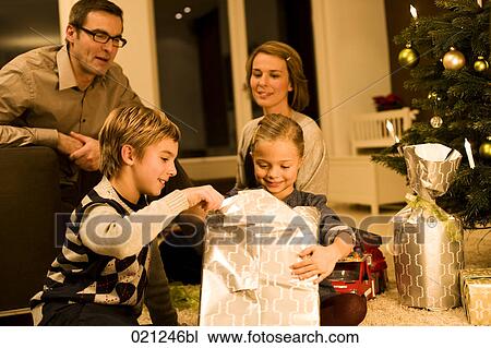 parents watching their children opening christmas presents on christmas eve View Large Photo Image Stock Image - parents watching their children opening christmas presents on christmas eve. Fotosearch