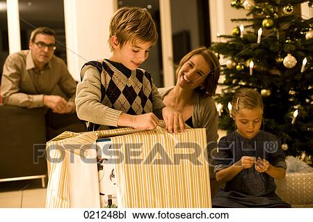 parents watching their children opening christmas presents on christmas eve View Large Photo Image Stock Image - parents watching their children opening christmas presents on christmas eve. Fotosearch