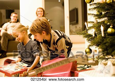 parents watching their children opening christmas presents on christmas eve View Large Photo Image Stock Image - parents watching their children opening christmas presents on christmas eve. Fotosearch