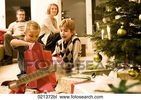 parents watching their children opening presents on christmas eve View Large Photo Image Stock Image - parents watching their children opening presents on christmas eve. Fotosearch