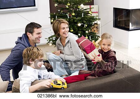 parents watching young girl holding present on christmas morning View Large Photo Image Stock Image - parents watching young girl holding present on christmas morning . Fotosearch