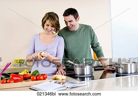 Stock Image - portrait of couple cooking in kitchen together. Fotosearch