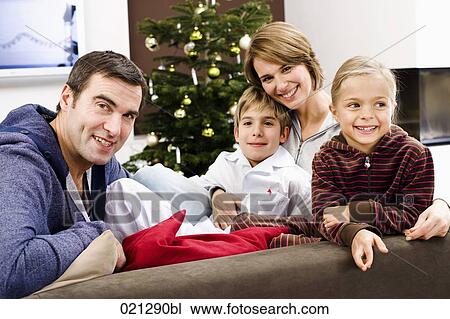 Stock Image - portrait of family sitting on sofa on christmas morning. Fotosearch