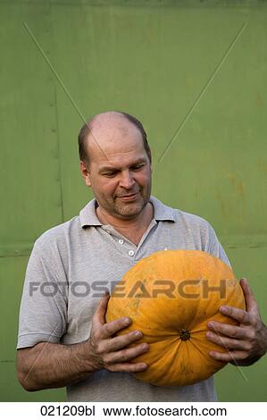 Stock Image - portrait of farmer holding pumpkin. Fotosearch