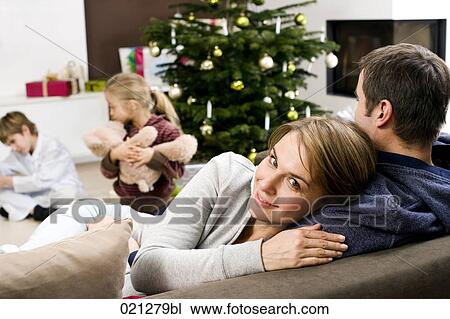 portrait of mother on sofa while children are playing in the background on christmas morning View Large Photo Image Stock Image - portrait of mother on sofa while children are playing in the background on christmas morning. Fotosearch