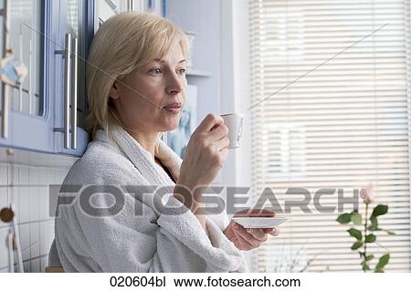 Stock Image - portrait of woman in bathobe drinking coffee. Fotosearch
