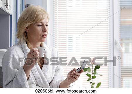 portrait of woman in bathrobe drinking coffee and checking mobile phone for text messages View Large Photo Image Stock Image - portrait of woman in bathrobe drinking coffee and checking mobile phone for text messages. Fotosearch