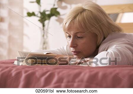 portrait of woman lying on bed reading book View Large Photo Image Stock Image - portrait of woman lying on bed reading book. Fotosearch