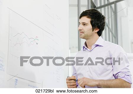 Stock Image - portrait of young businessman in front of whiteboard. Fotosearch
