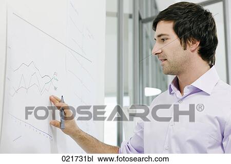 Stock Image - portrait of young businessman in front of whiteboard. Fotosearch