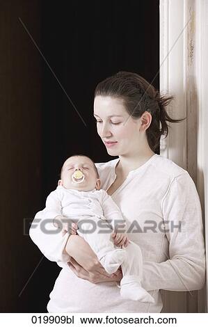 Stock Image - portrait of young mother holding her sleeping baby girl. Fotosearch