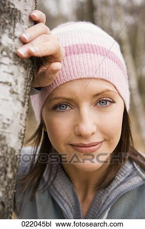 Stock Image - portrait of young woman leaning against tree in autumn. Fotosearch