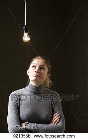 Stock Image - portrait of young woman under light bulb. Fotosearch