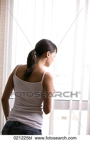 rear view of young woman looking through window View Large Photo Image Stock Image - rear view of young woman looking through window. Fotosearch