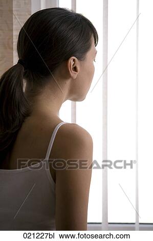 rear view of young woman looking through window View Large Photo Image Stock Image - rear view of young woman looking through window. Fotosearch