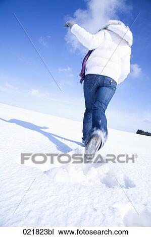 rear view of young woman running through snow View Large Photo Image Stock Image - rear view of young woman running through snow. Fotosearch
