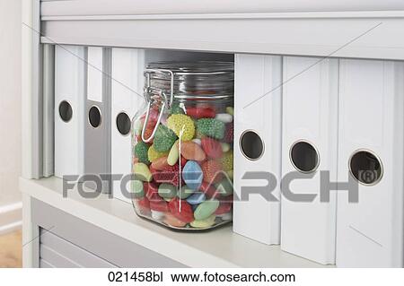 Stock Image - still life of jar with sweets in filing cabinet. Fotosearch