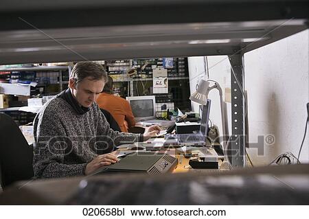 Stock Image - two workers at computer repair shop. Fotosearch
