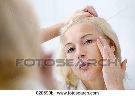 woman in front of mirror applying skin cream View Large Photo Image Stock Image - woman in front of mirror applying skin cream. Fotosearch