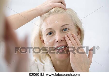 woman in front of mirror applying skin cream View Large Photo Image Stock Image - woman in front of mirror applying skin cream. Fotosearch