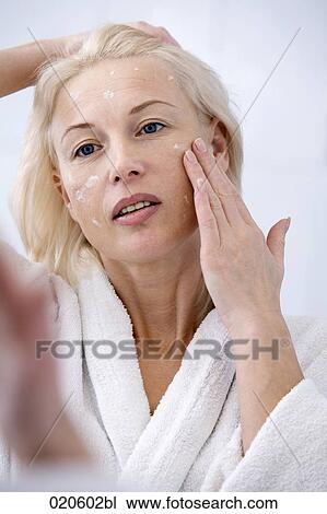 woman in front of mirror applying skin cream View Large Photo Image Stock Image - woman in front of mirror applying skin cream. Fotosearch