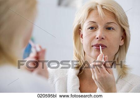 woman in front of mirror applying lip-gloss View Large Photo Image Stock Image - woman in front of mirror applying lip-gloss. Fotosearch
