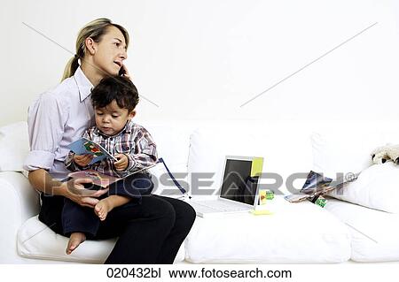 woman sitting on sofa with little son on lap and talking on mobile phone View Large Photo Image Stock Image - woman sitting on sofa with little son on lap and talking on mobile phone. Fotosearch