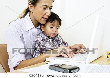woman working from home with laptop computer sitting with little son at table View Large Photo Image Stock Image - woman working from home with laptop computer sitting with little son at table. Fotosearch