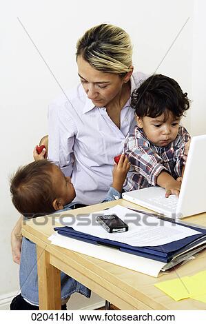 woman working from home with laptop computer sitting with little sons at table View Large Photo Image Stock Image - woman working from home with laptop computer sitting with little sons at table. Fotosearch