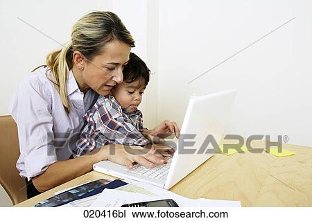 woman working from home with laptop computer sitting with little son at table View Large Photo Image Stock Image - woman working from home with laptop computer sitting with little son at table. Fotosearch